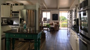 A spacious kitchen with modern appliances, a dining area with a wicker chair, and a balcony with outdoor furniture.