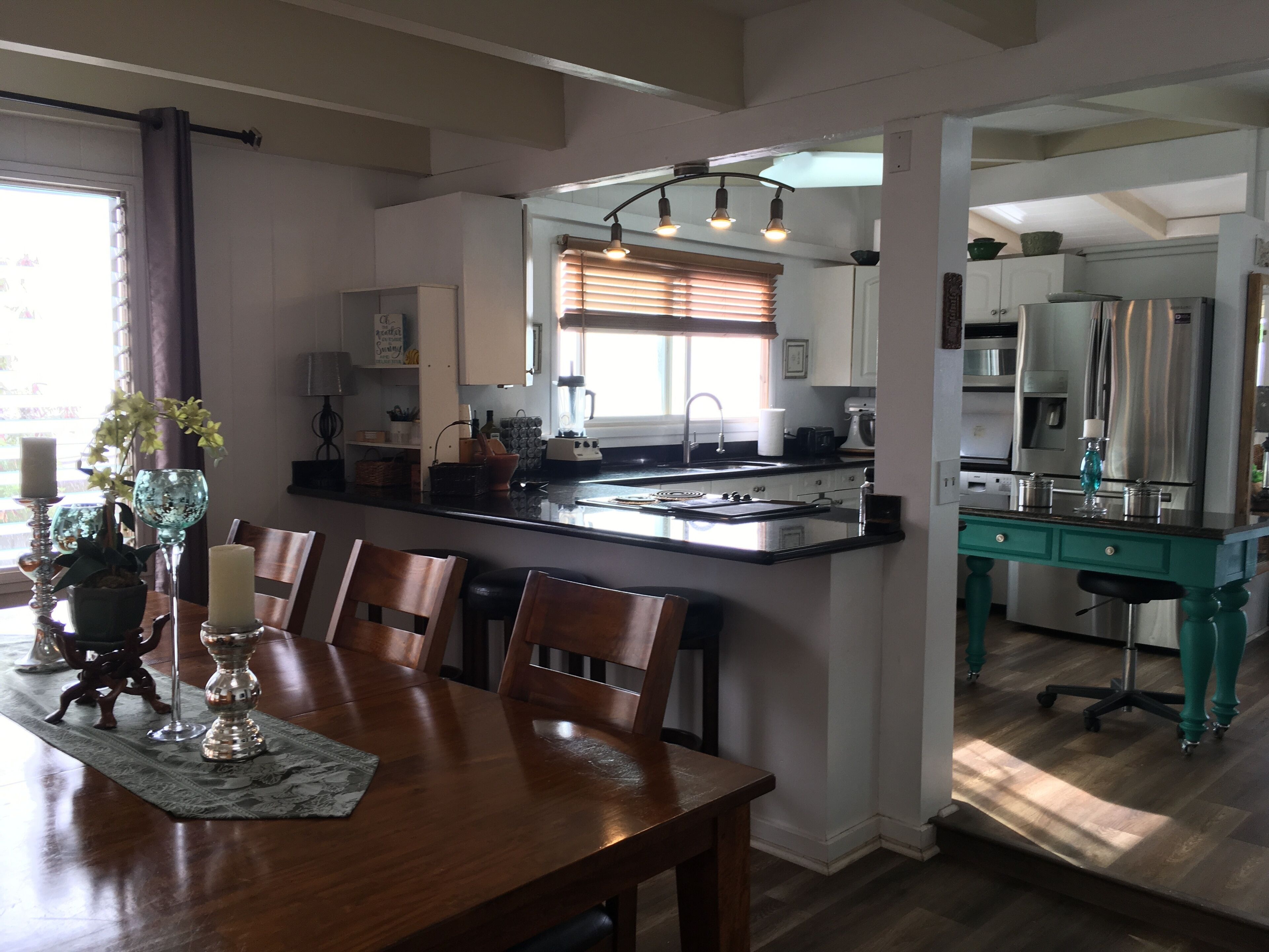 Een moderne keuken met een centraal eiland, een eethoek met een houten tafel en stoelen, en uitzicht op de aangrenzende eetkamer.