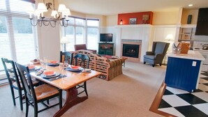 A dining area with a wooden table set for four, a fireplace, and a television in the background. - HILTON GVC NEW YEAR'S 2026-27 - 6 Nights (Mont-Tremblant)