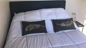 A bed with a dark headboard, grey bedding, and two black pillows with a feather design. - STUDIO AWESOMENESS FOR YOU LMU SILICON BCH VENICE (Los Angeles)