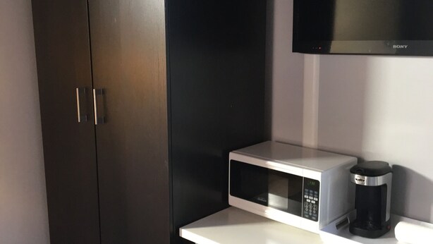A compact room with a white desk, a microwave, a coffee maker, and a TV mounted on the wall. - STUDIO AWESOMENESS FOR YOU LMU SILICON BCH VENICE (Los Angeles)