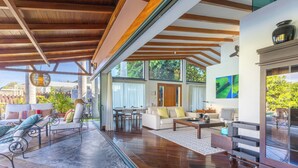 A spacious living area with a wooden ceiling, large windows, and a view of greenery outside. - Villa La Canela by VillaGranCanaria (San Bartolomé de Tirajana)