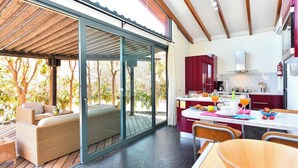 A modern kitchen with a dining area, a large sliding glass door leading to an outdoor deck, and a view of trees. - Villa La Canela by VillaGranCanaria (San Bartolomé de Tirajana)