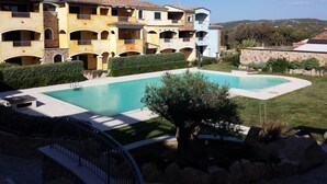 Un hotel con piscina, varios balcones y vistas del paisaje circundante.