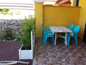 Un patio con mesa y sillas, un muro de piedra y una jardinera con plantas.