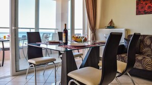A dining area with a glass table, chairs, and a bottle of wine.