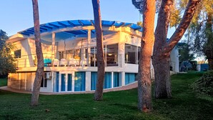 A modern house with a curved roof and large windows, surrounded by trees. - "ALL NATURE"- Private Oasis.15km to airport. 25 km to Valencia. Sleeps 14+3 (El Rellano)