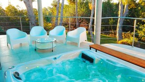 A hot tub with four white chairs and a table, surrounded by a wooden bench and a glass table, set on a patio with a view of trees. - "ALL NATURE"- Private Oasis.15km to airport. 25 km to Valencia. Sleeps 14+3 (El Rellano)