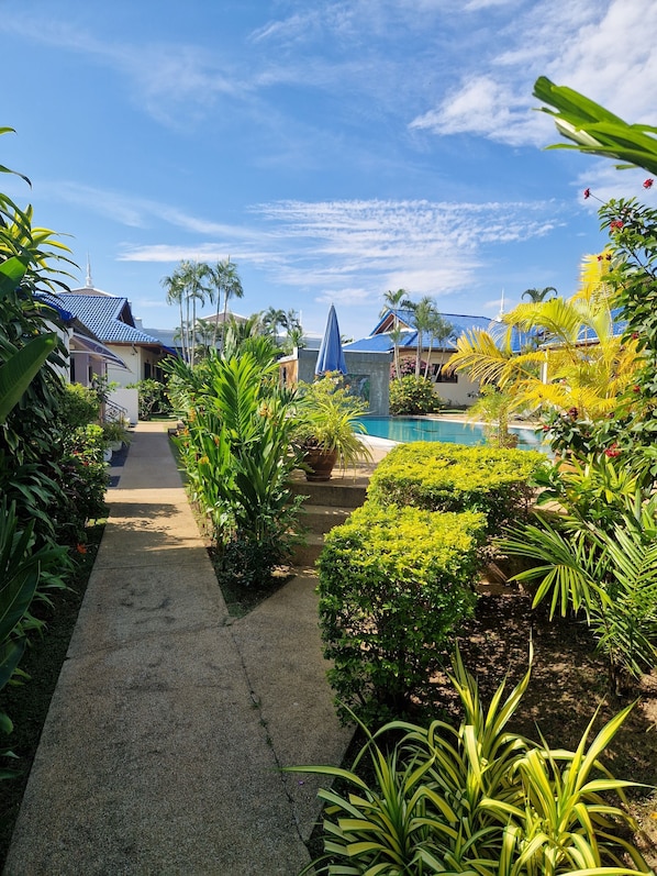 A tropical resort with a swimming pool, lush greenery, and traditional architecture.