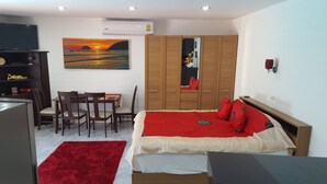 A bedroom with a bed, a desk with chairs, a TV, and a painting of a sunset. - LARGE VILLA SWIMMING POOLS TROPICAL GARDEN SEA GOLF RELAXATION 6 /12 ADULTS (Phuket)