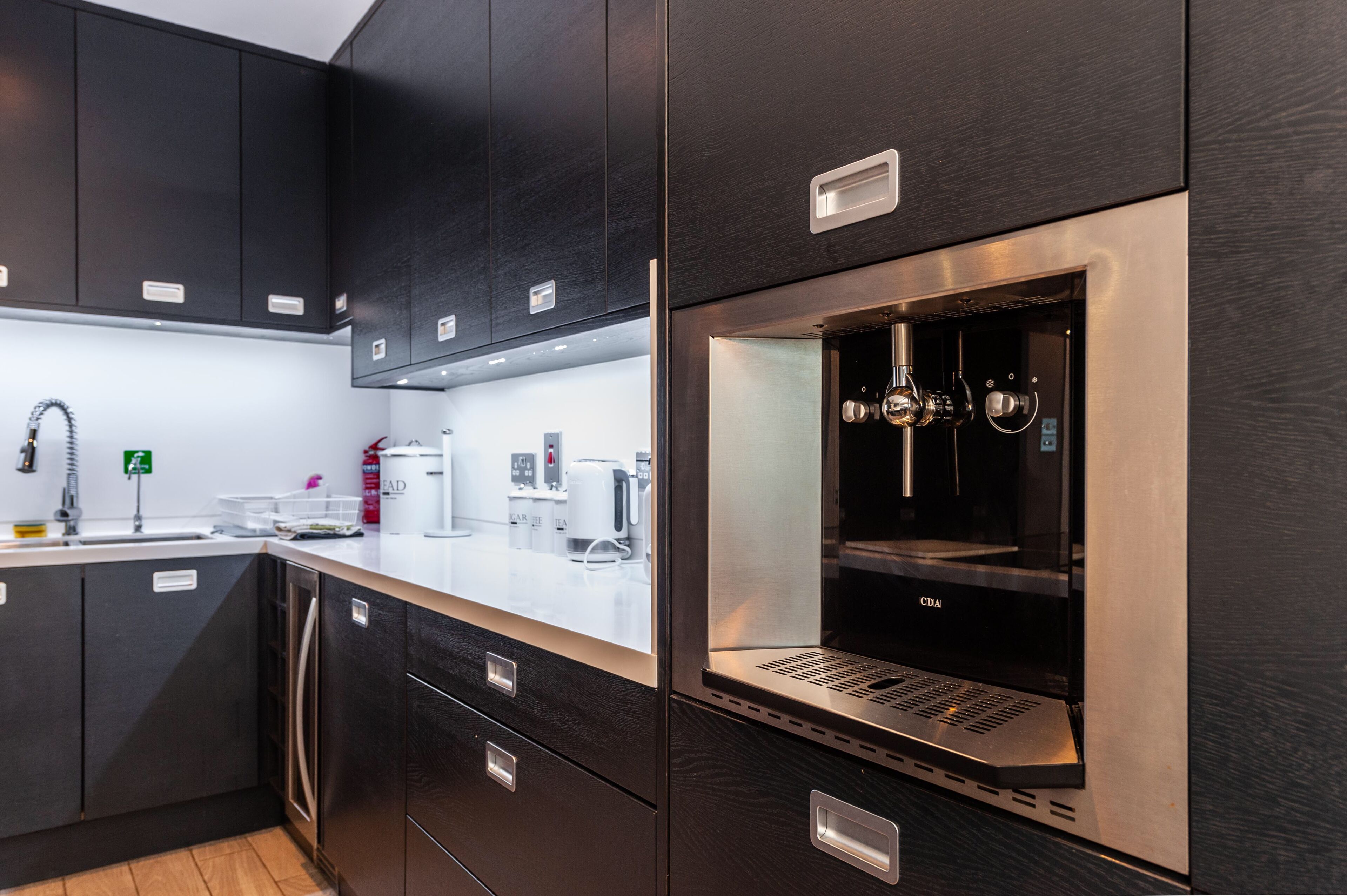 Een moderne keuken met donkere kastjes, roestvrijstalen apparatuur en een inbouwoven.