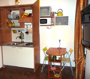A compact kitchen with a sink, a microwave, and a small dining area with a table and chairs.