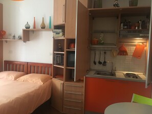 A compact bedroom with a single bed and a small kitchenette.