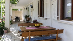 A covered outdoor seating area with a table, chairs, and a bowl of fruit. - Apartment in Dubrovnik with swimming pool and sea view   (A1) (Dubrovnik Mokosica)