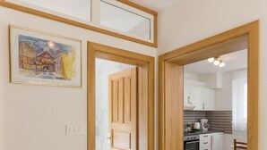 A hallway leading to a kitchen with wooden doors and a framed painting on the wall. - Apartment in Dubrovnik with swimming pool and sea view   (A1) (Dubrovnik Mokosica)