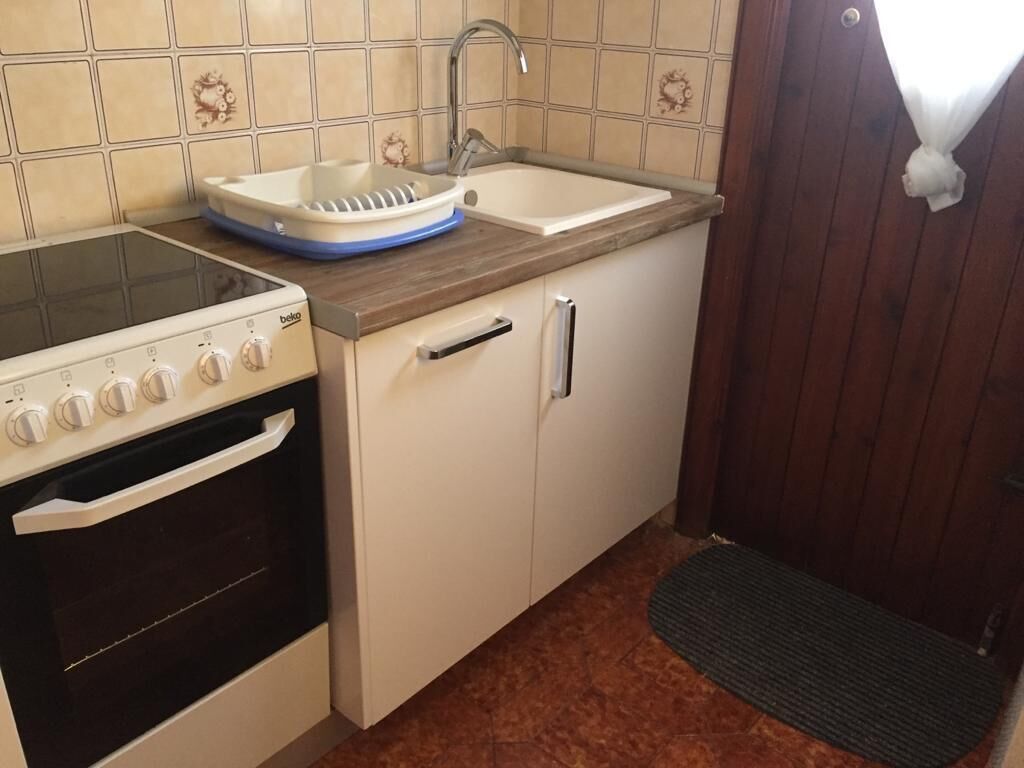 Une cuisine de taille réduite, équipée d’une cuisinière, d’un évier et de meubles de rangement en bois.