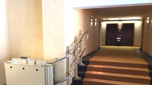 A hotel lobby with a carpeted staircase, a reception desk, and a wall-mounted elevator. - 2-room, internet, 3 beds, mountain view and garage (Bad Reichenhall)