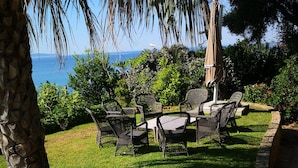 Un patio con mobiliario de mimbre y vista al océano.