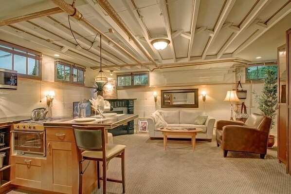 A compact living space with a kitchenette, a dining area, and a seating area with a sofa and armchairs. - Suite I: Private Studio in our classic home near Woodland Park Zoo (Seattle)