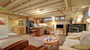 Een ruime woonkamer met een keuken, een open haard en een televisie.
