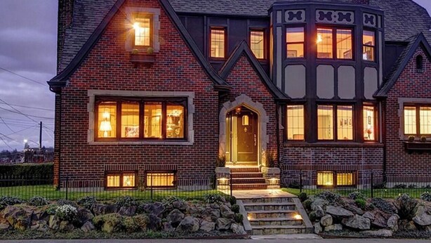 Une grande maison à deux étages, dotée d’une cheminée imposante, d’une entrée bien éclairée et de fondations en pierre.
