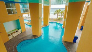 Une piscine intérieure avec vue sur l’océan, entourée de murs et de piliers de couleur jaune.