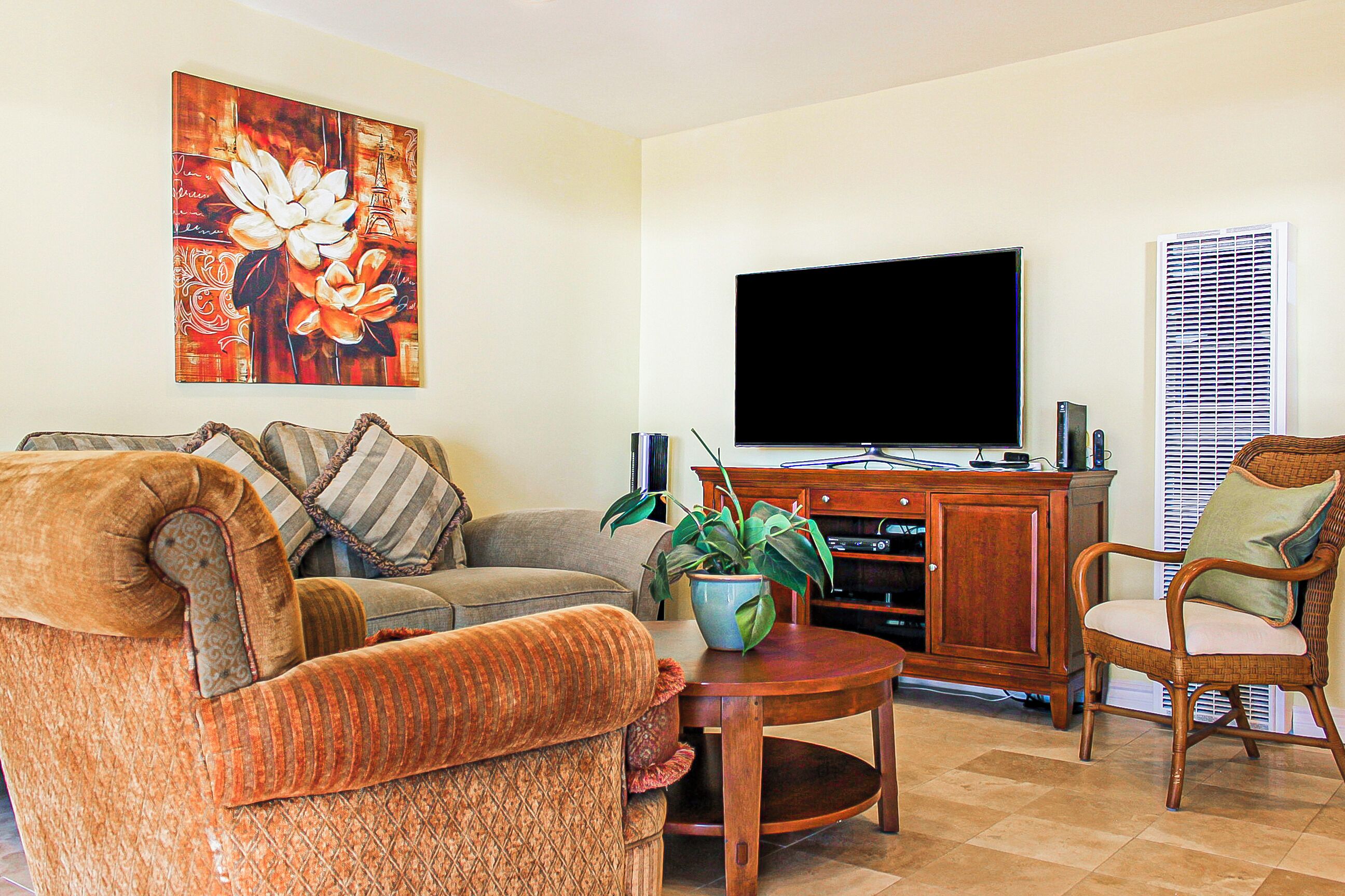 A living room with a sofa, armchair, TV, and a cabinet.