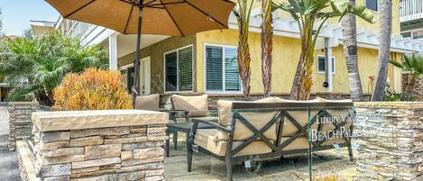 A patio with stone walls, a table with chairs, and a large umbrella.