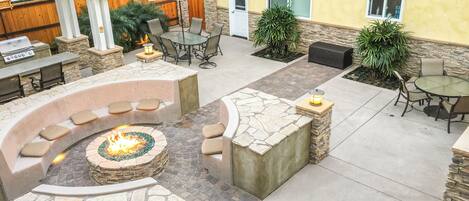 An outdoor patio area with stone seating, a fire pit, and tables and chairs.