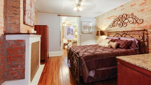 A bedroom with a brick wall, a wooden bed, and a ceiling fan.