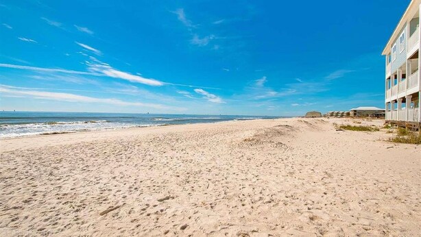 A beach with a building on the right. - 2 Minute walk to the secluded beaches of Fort Morgan! Pet friendly! Quiet Space! (Gulf Shores)