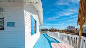 A wooden deck with a blue railing, white walls, and a clear blue sky. - 2 Minute walk to the secluded beaches of Fort Morgan! Pet friendly! Quiet Space! (Gulf Shores)
