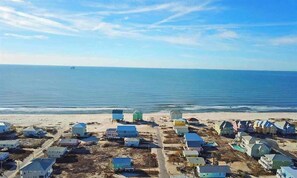 A coastal area with numerous small, colorful houses along the beach, a clear sky, and the ocean in the background. - 2 Minute walk to the secluded beaches of Fort Morgan! Pet friendly! Quiet Space! (Gulf Shores)