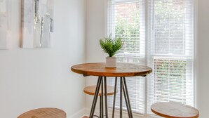Ein Essbereich mit einem runden Tisch, vier Hocker, einer Pendelleuchte und einem Blumentopf.