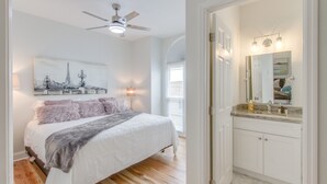 Ein Schlafzimmer mit einem Bett, einem Deckenventilator, einem Nachttisch und einer Wandlampe.