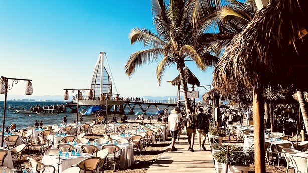 A beachside restaurant named El Dorado with outdoor seating and a view of the sea and a bridge in the background. - Los Muertos Beachfront Art Condo with Pano View:  Best Romantic Zone Location (Puerto Vallarta)
