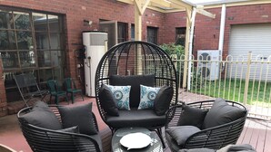 Un patio con mobiliario de mimbre, incluyendo una silla y una mesa.