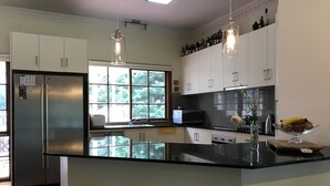 Una cocina moderna con armarios blancos, un refrigerador de acero inoxidable, un microondas y una isla grande con taburetes.
