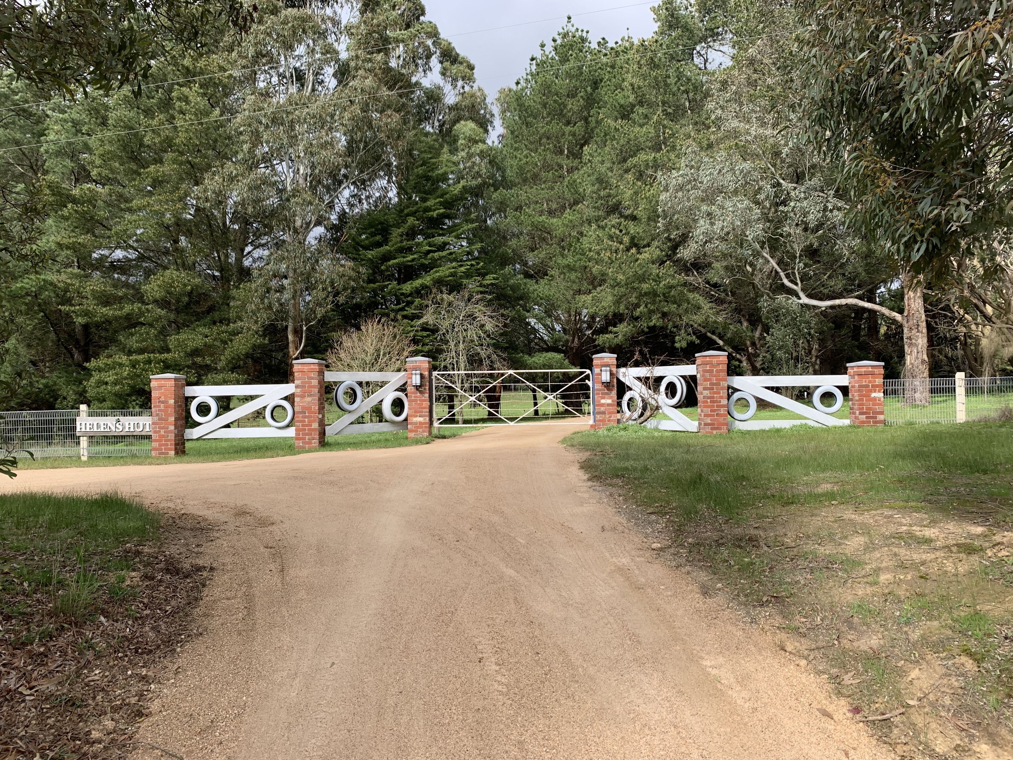 Una entrada protegida por un portón con un letrero que dice "Eden's Hotel" y una puerta decorativa con diseños de neumáticos.