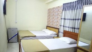 Ein kleines, schlichtes Zimmer mit zwei Einzelbetten, einem kleinen Tisch, einem Spiegel und einem Wandheizkörper.