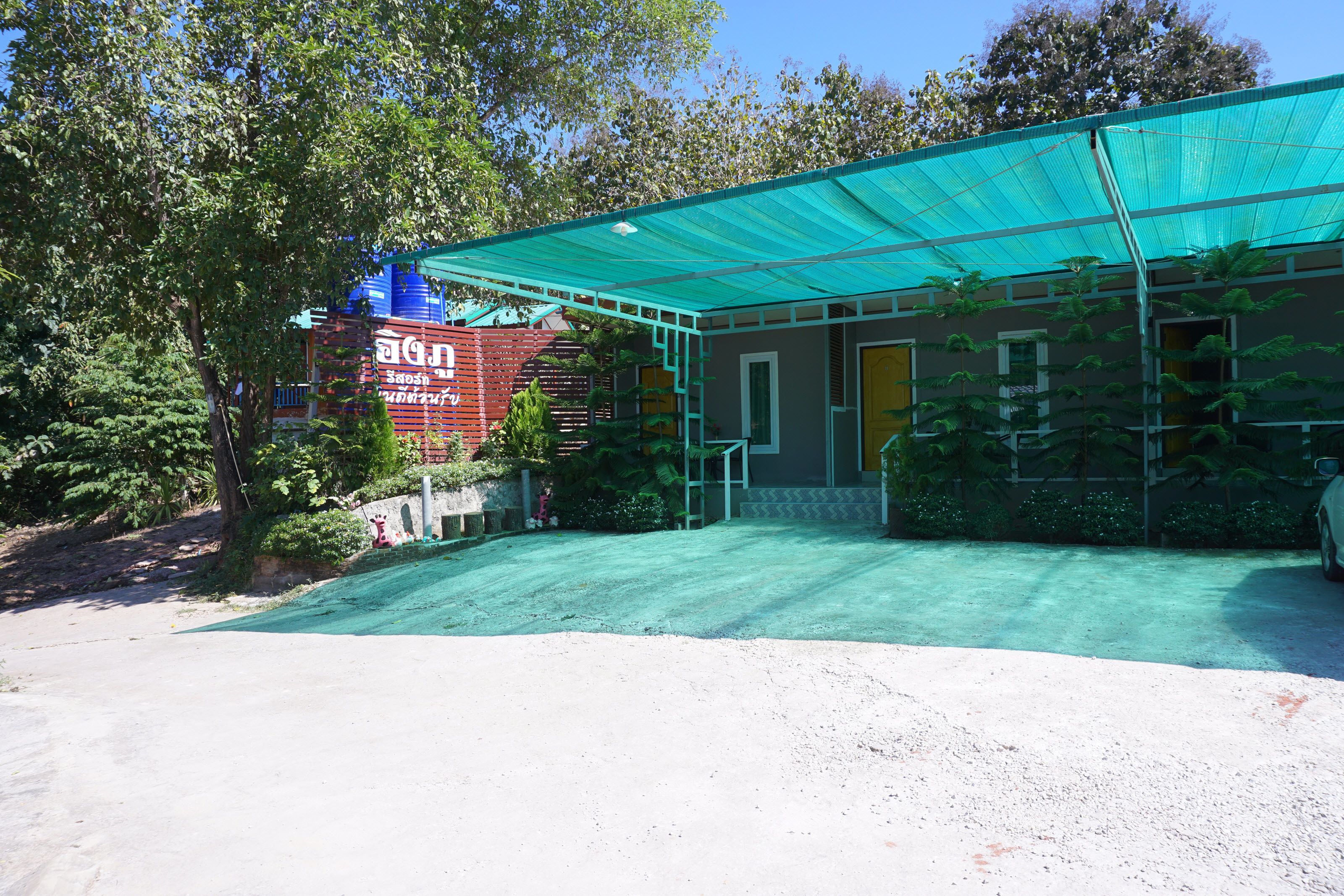 A building with a green roof, surrounded by trees and a gravel area.