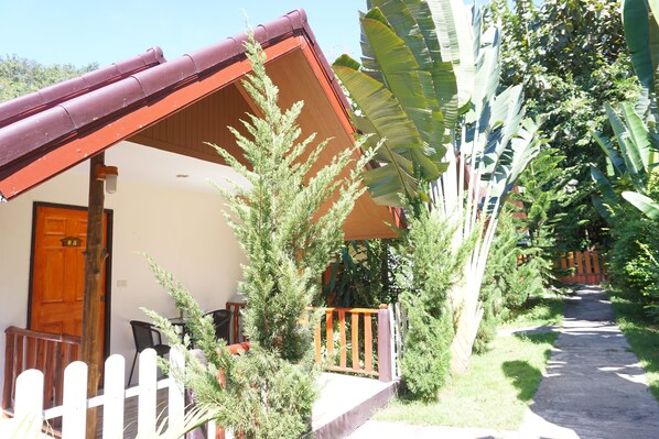 A house with a wooden door, a porch with a railing, and a pathway leading to a wooden fence. - Ing Phu Resort (Dan Sai)