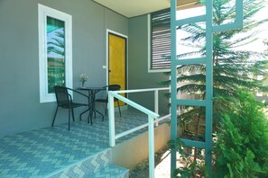 A balcony with a tiled floor, a small table with chairs, and a yellow door. - Ing Phu Resort (Dan Sai)