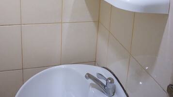 Un baño con un lavamanos blanco, un espejo y un estante sobre el lavamanos.