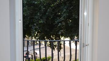 Una porta aperta che dà su un balcone con vista su una strada e auto parcheggiate.