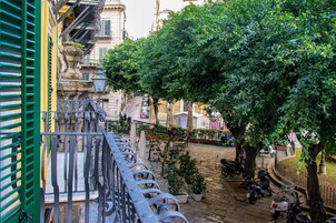 Un patio con un árbol, plantas en macetas y una scooter estacionada cerca de la barandilla.