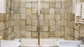 A bathroom with a glass-enclosed shower, two sinks, and a tiled wall.