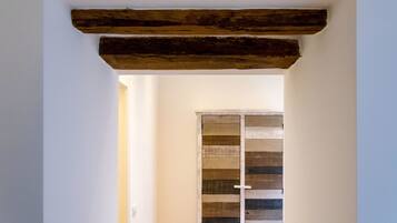 A doorway with a rustic wooden beam ceiling and a striped wooden door.