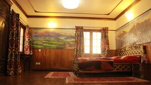 A traditional room with a wooden floor, a bed with ornate headboard, and a large landscape painting on the wall. - Tokha Holiday Home (Tohka)