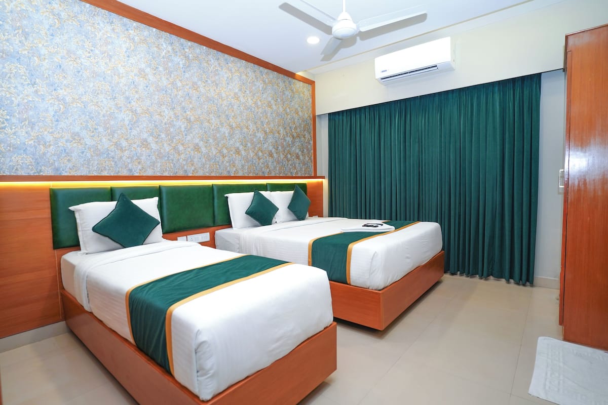 A hotel room with two beds, a ceiling fan, an air conditioning unit, and a green curtain.